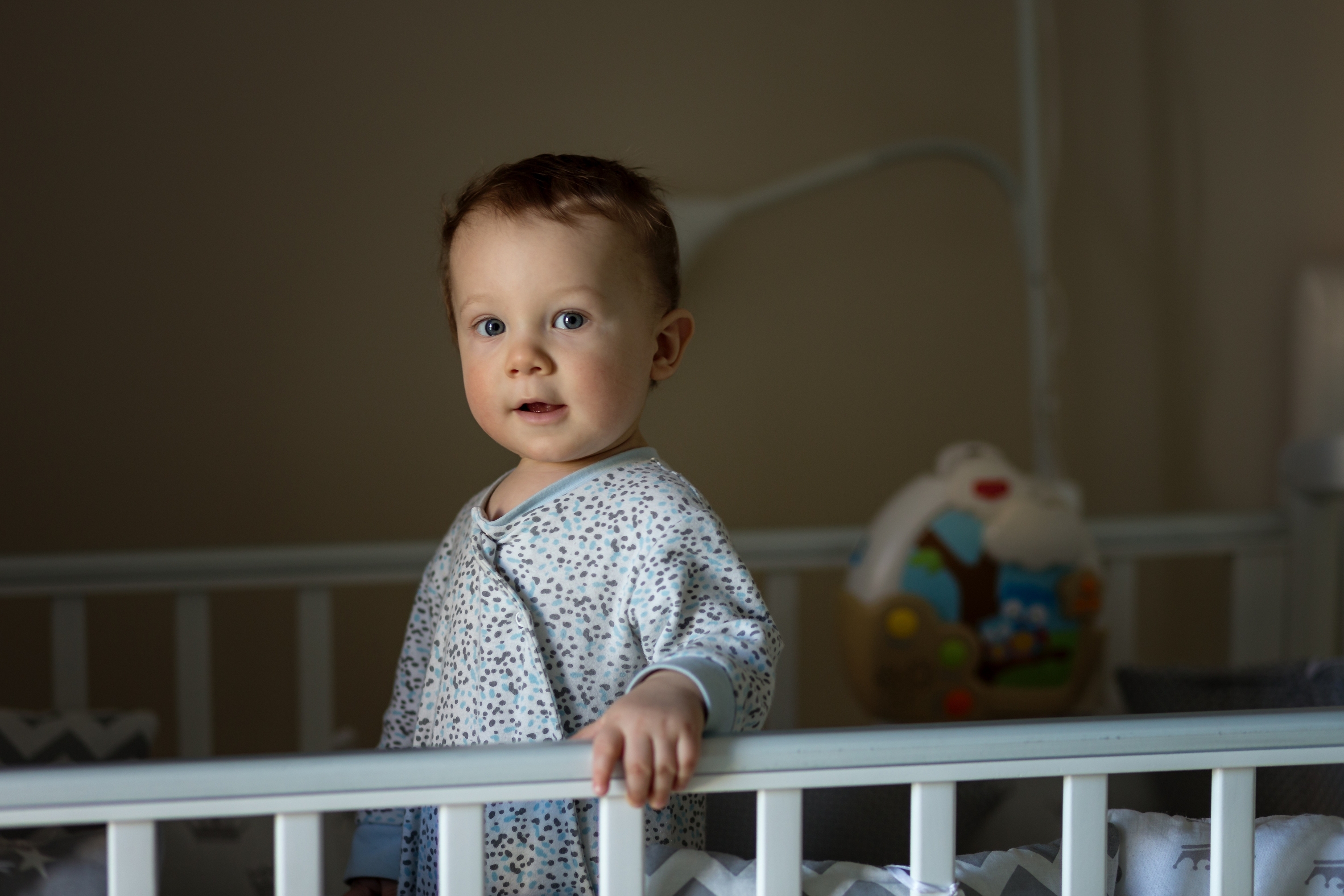 Baby standing in a crib at bedtime