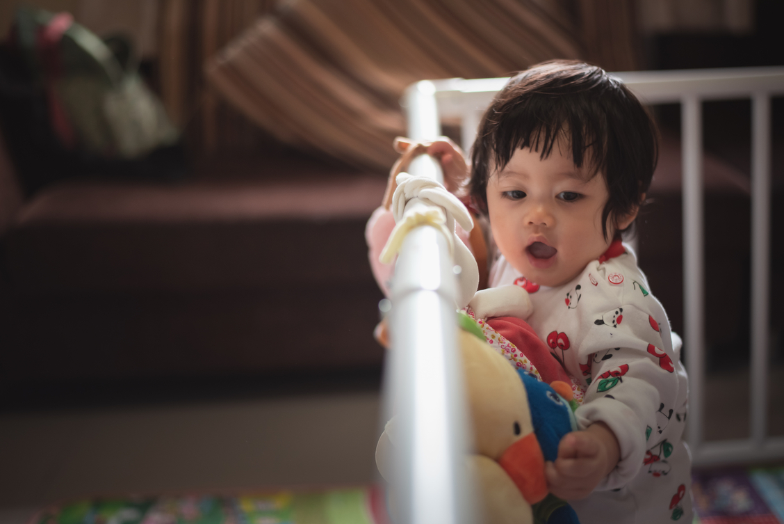 Toddler standing in a crib at nighttime looking alert