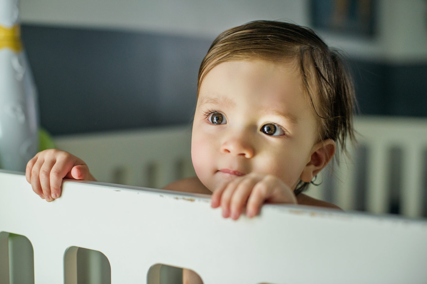 Toddler standing in a crib holding the rail at bedtime