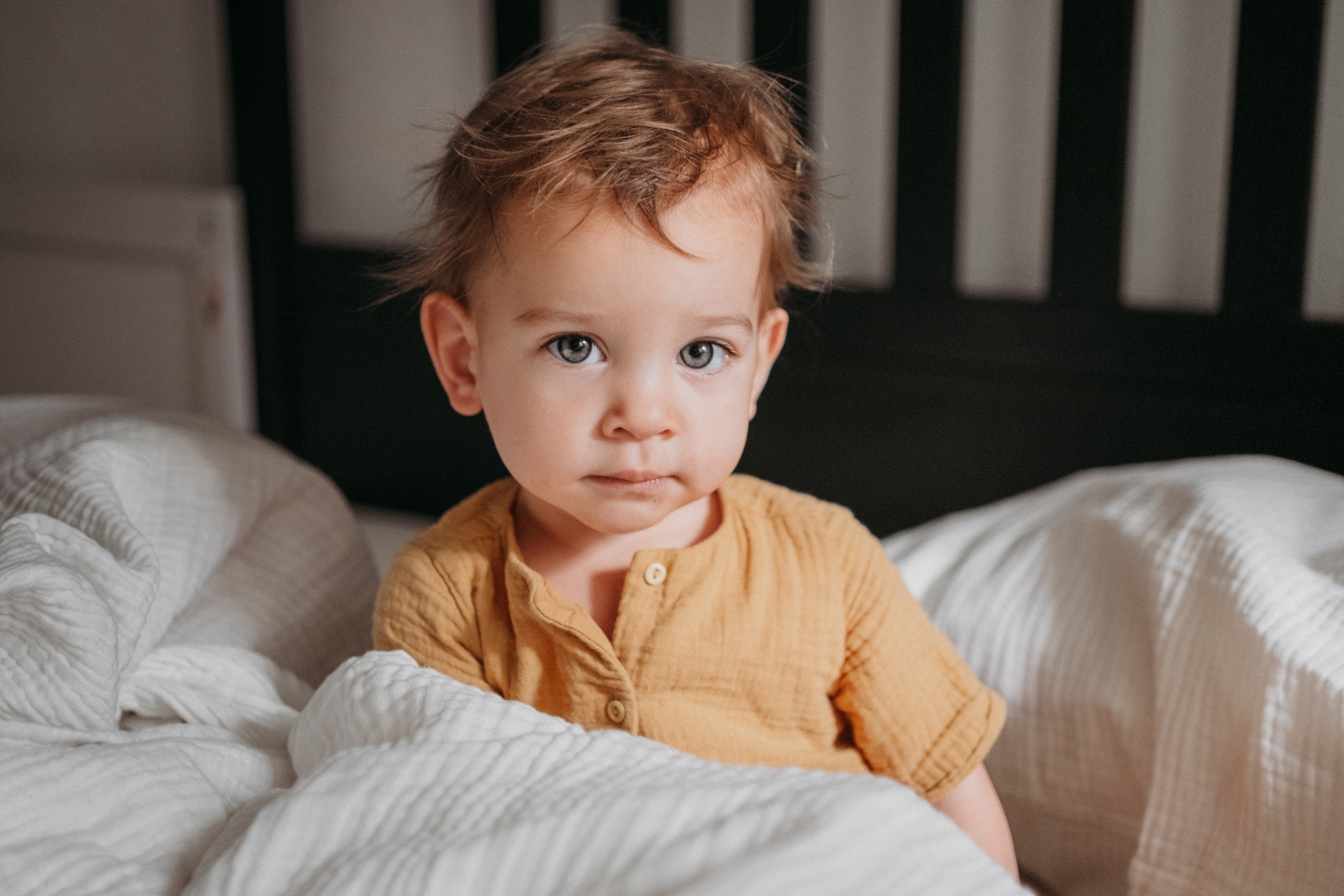 Toddler sitting upright in bed at night looking alert