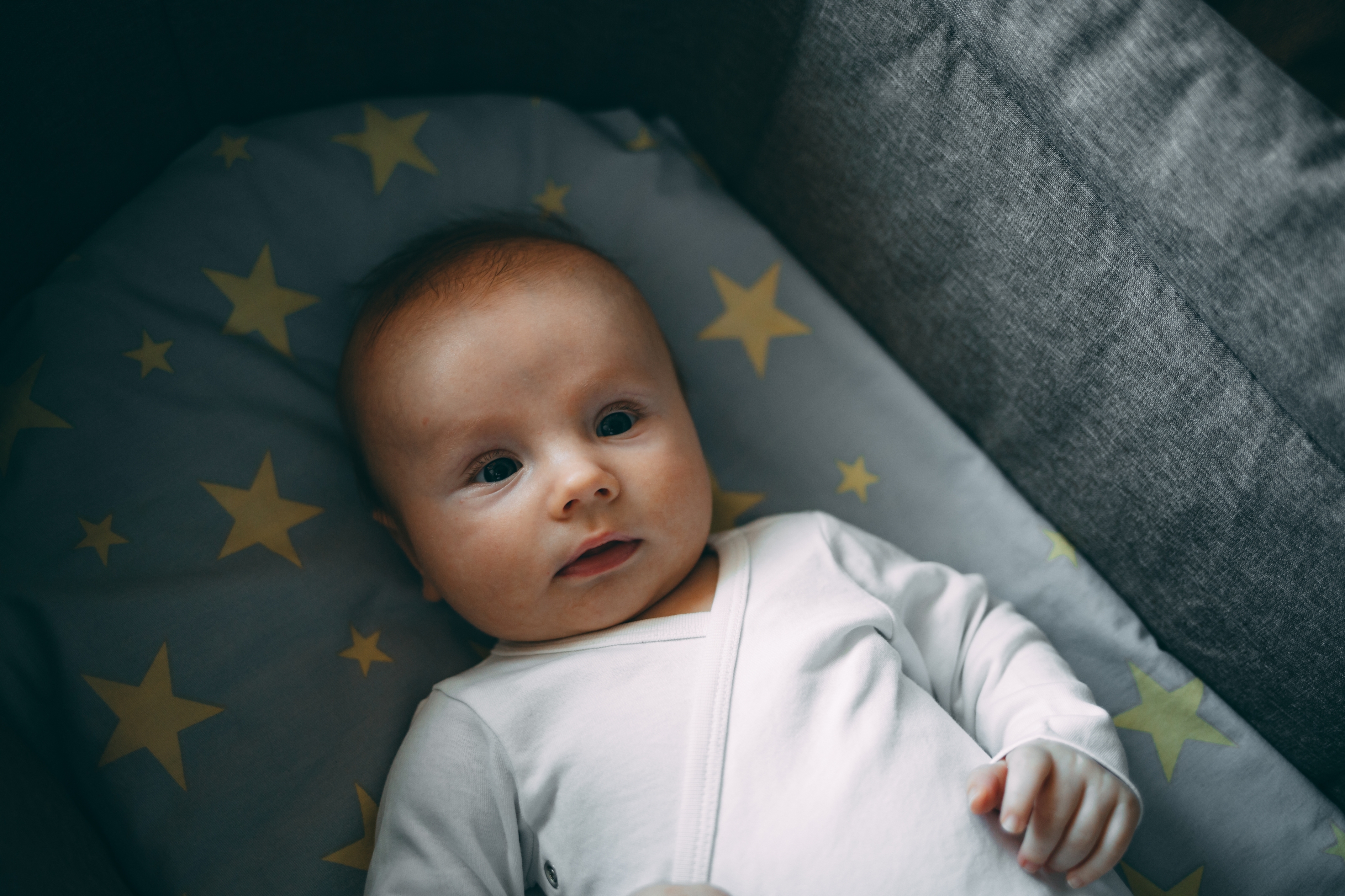Baby lying awake in a dimly lit crib at night