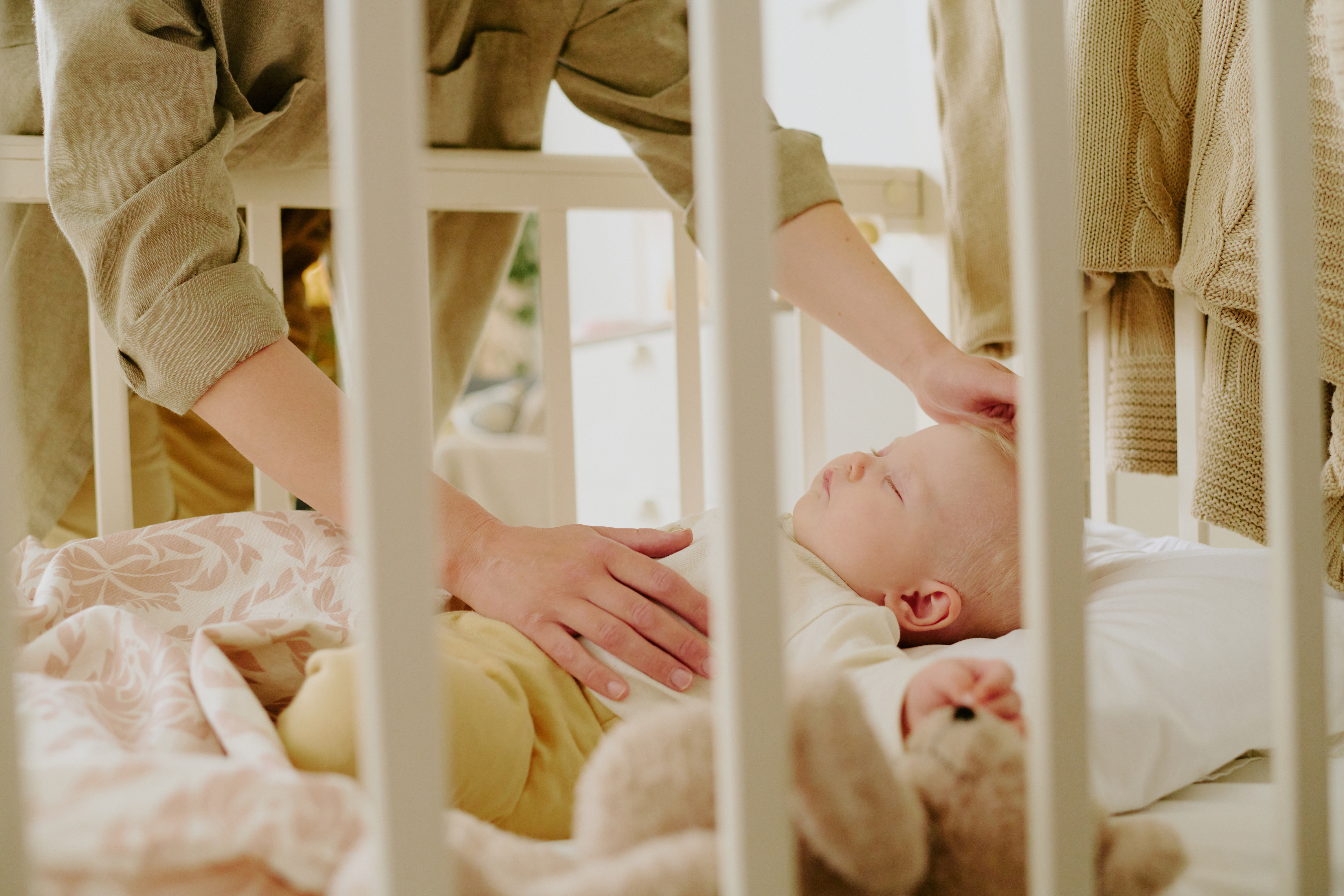 Caregiver reassuring baby beside the crib