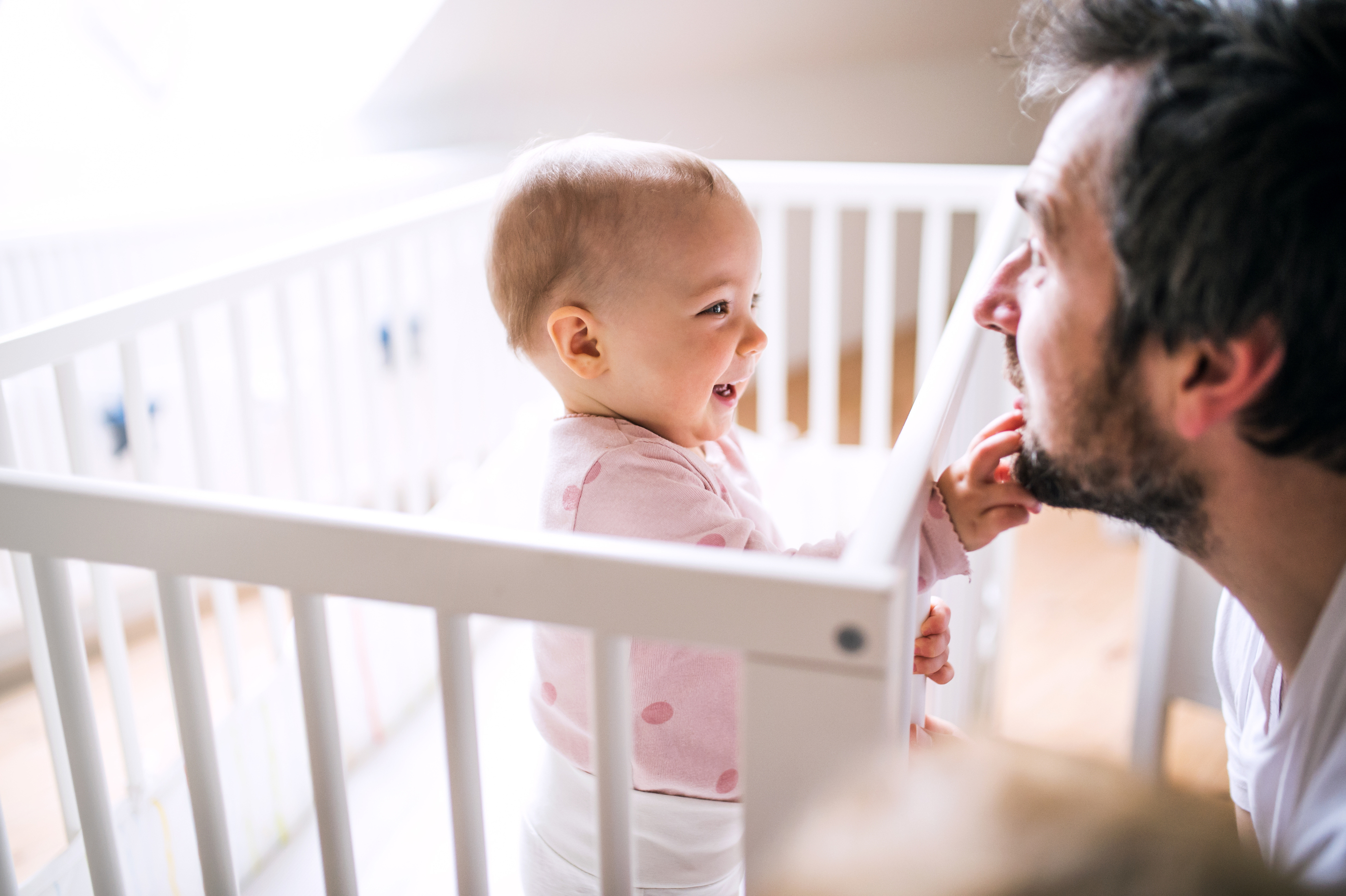 Parent calmly reassuring baby beside crib