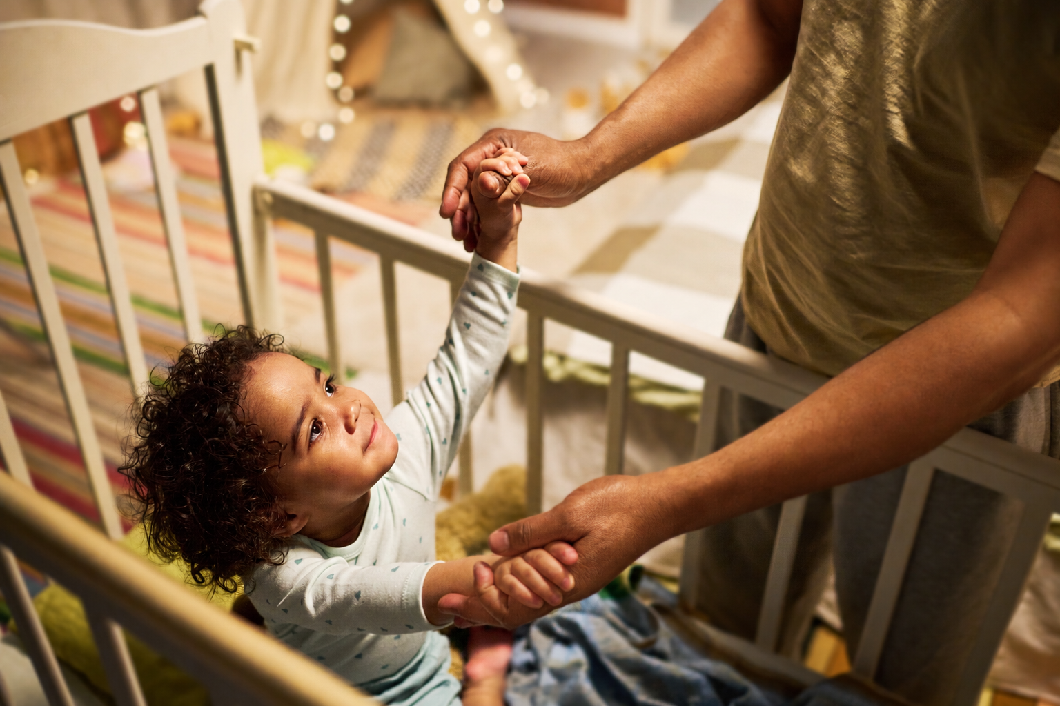 Toddler clinging to a parent's arm at bedtime