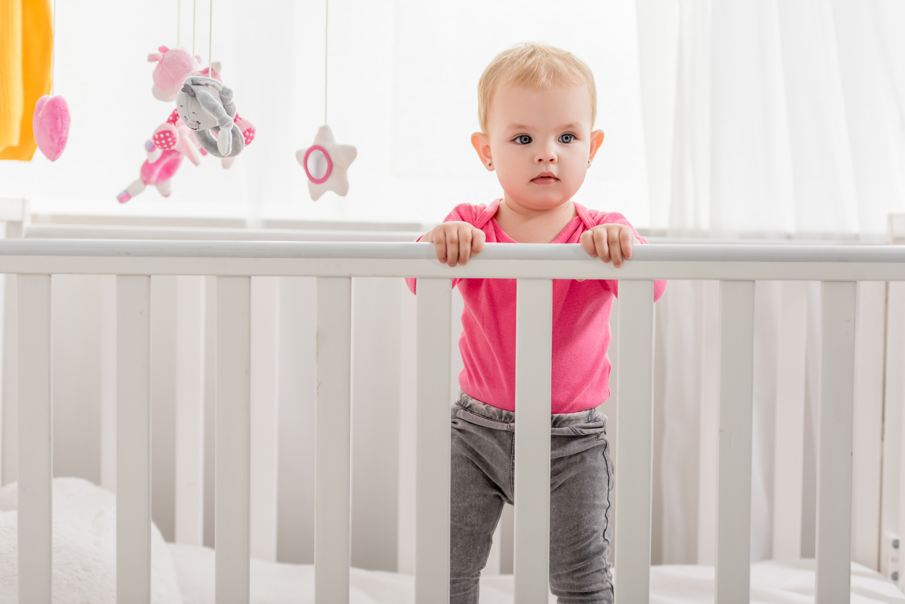 Toddler awake in a crib during daytime with sunlight