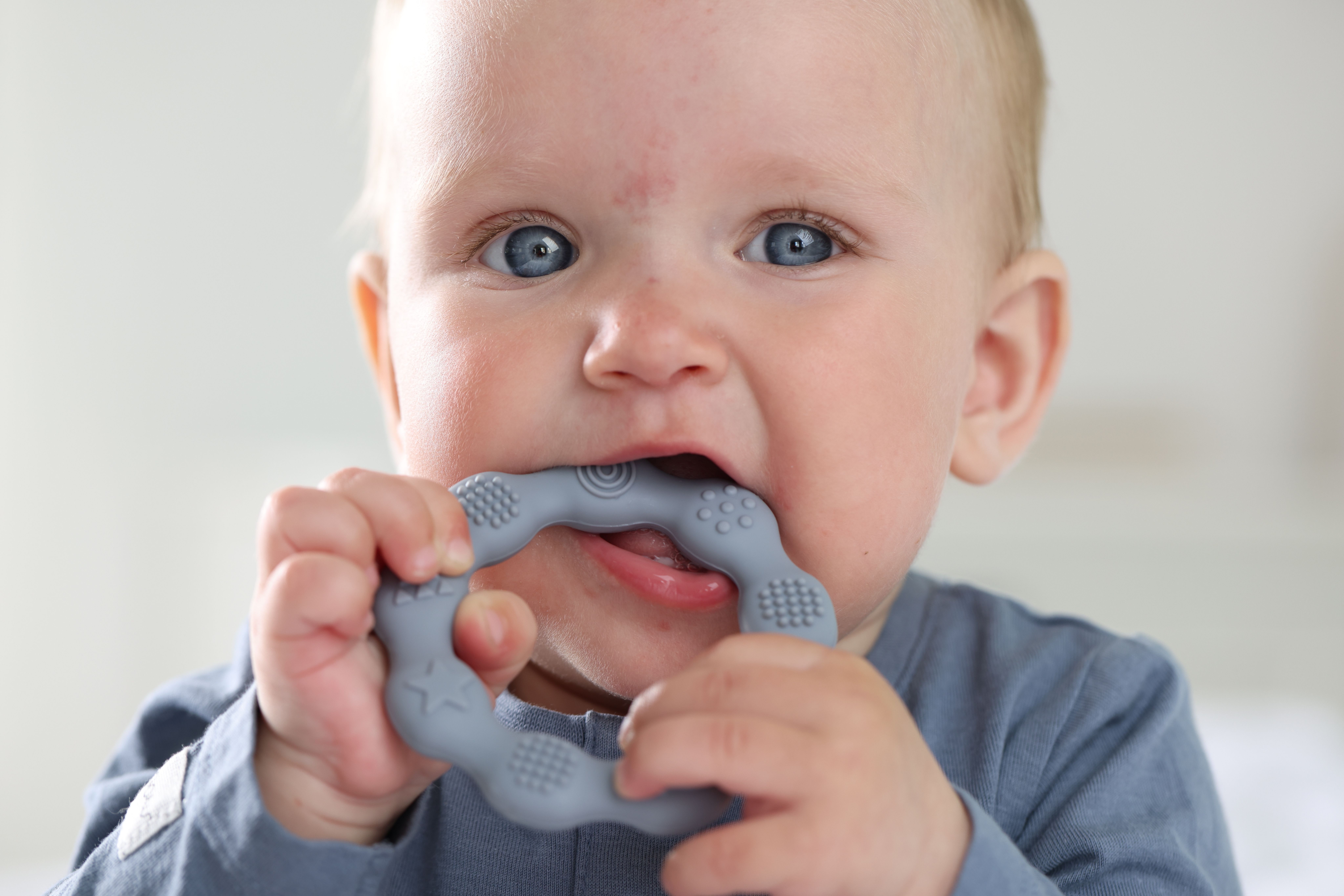 Close-up of a toddler chewing on a teething ring