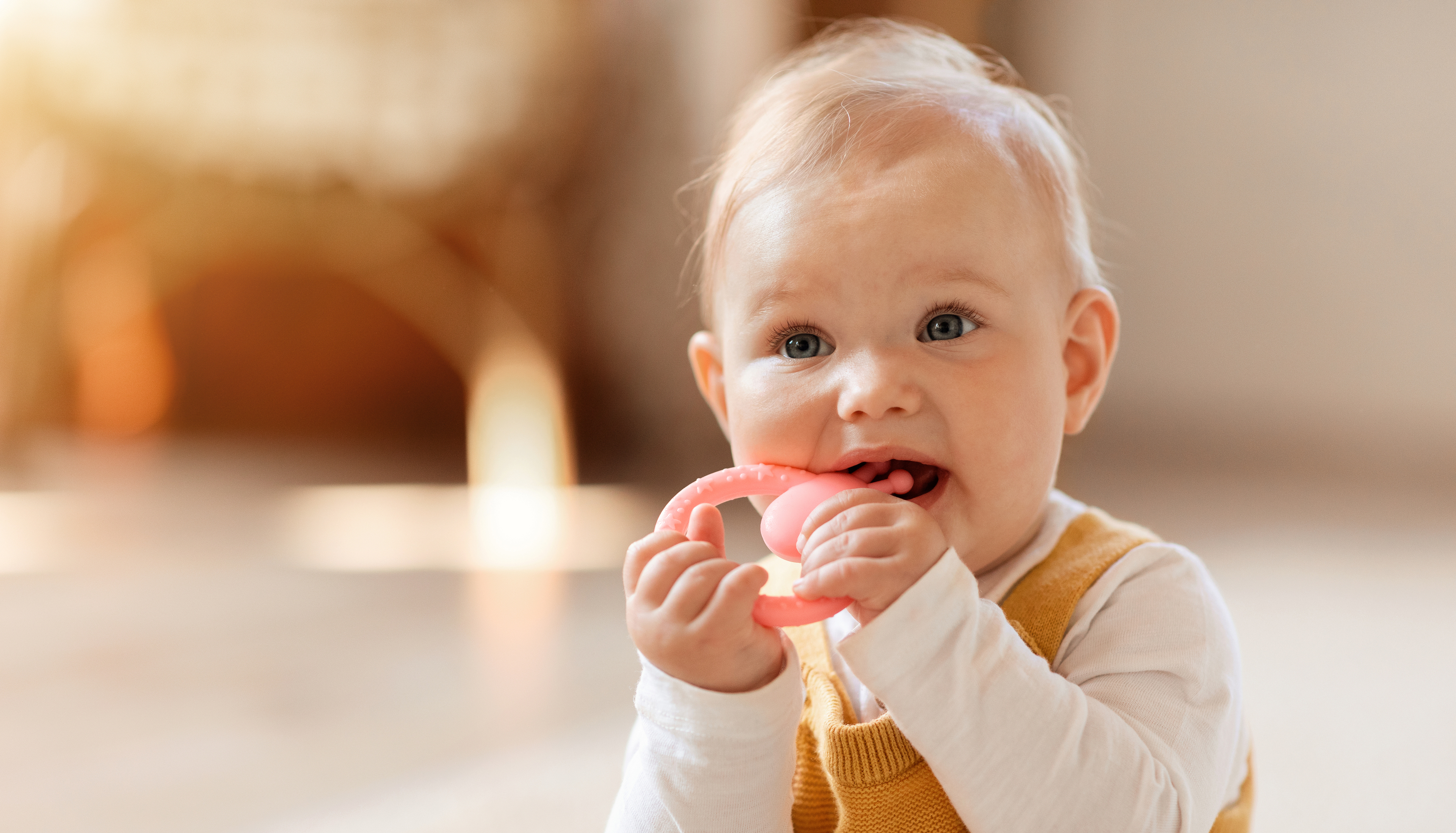 Baby chewing a teething ring at home