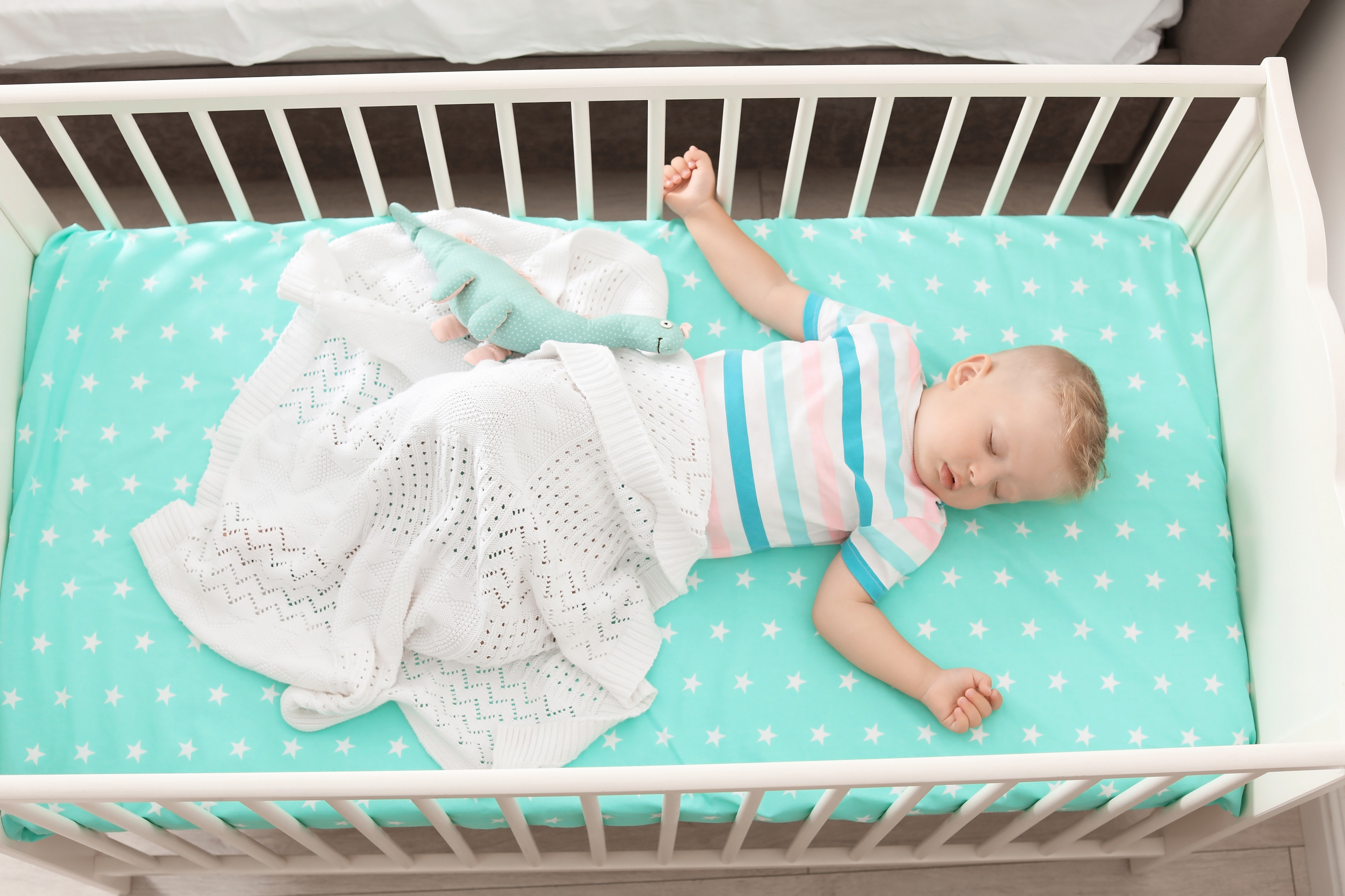 Toddler peacefully asleep in a crib with soft blankets